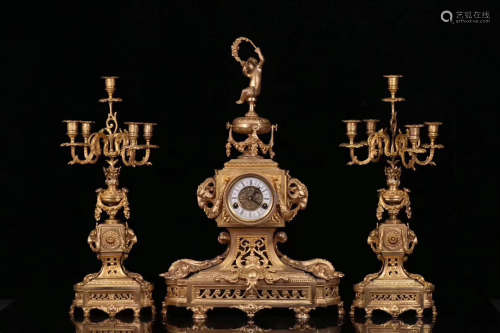 A CENTURIAL GILT BRONZE TABLE CLOCK WITH A PAIR OF CANDLESTICKS