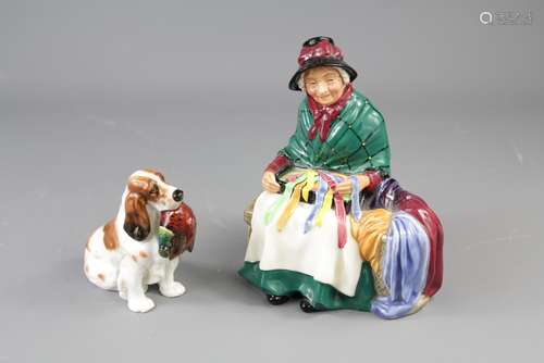 Royal Doulton Figure of a Seated Lady Selling Silks and Ribbons, the figure approx 14 x 16 cms, together with a Royal Doulton figurine of a spaniel with pheasant, approx 10 x 9 cms