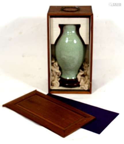 A Chinese celadon glazed vase with embossed foliate decoration, in a silk lined wooden carry case,