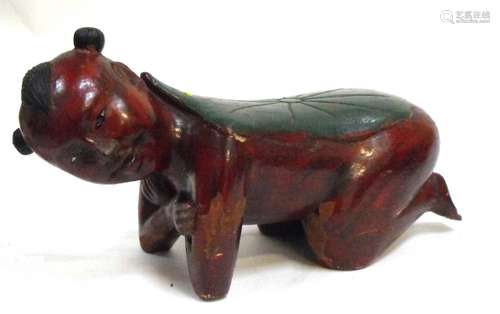 A Chinese polychrome and lacquer carved wooden head rest or pillow in the form of a kneeling boy,