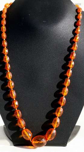 An amber like necklace comprising forty four graduated faceted oval beads, the largest 26cmm.