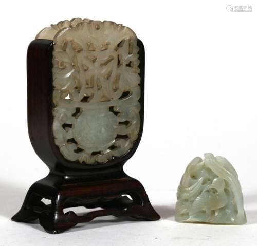 A Chinese pierced jade carving mounted on a hard wood stand 10cm (4 ins) high, together with a