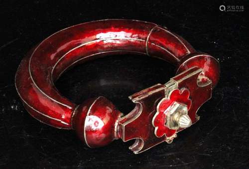 A large Indian red enamel on white metal bangle, 12.5cms (5ins) diameter.