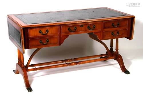 A reproduction yew wood writing table with inset leather top and drop flaps above an arrangement