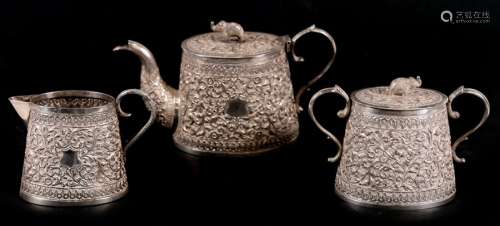 An Indian silver three-piece tea set with all over chased foliate decoration and elephant finials,
