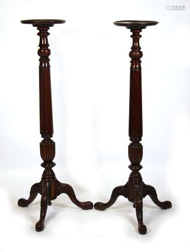 A pair of mahogany torcheres, the turned column on acanthus capped tripod legs with ball & claw