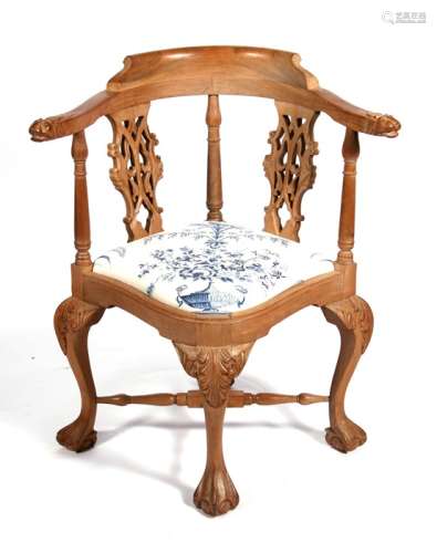 A Georgian style walnut corner chair with carved lion mask arms and pierced back splats, on acanthus