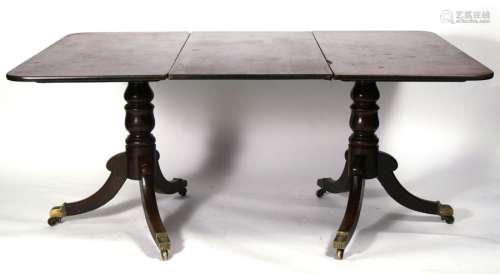 A Georgian mahogany twin pillar dining table on turned supports and tripod bases, with one extra