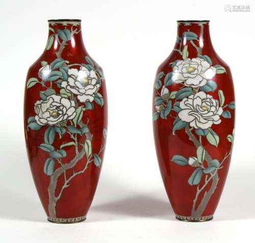 A pair of Japanese cloisonne vases decorated with flowers on a red ground, 31cms (12.25ins) high (