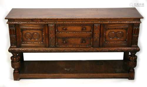 A Jacobean style oak dresser base with two central drawers flanked by cupboards, on turned &