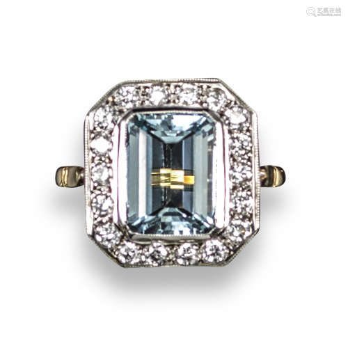 An aquamarine and diamond cluster ring, the emerald-cut aquamarine is set within a surround of