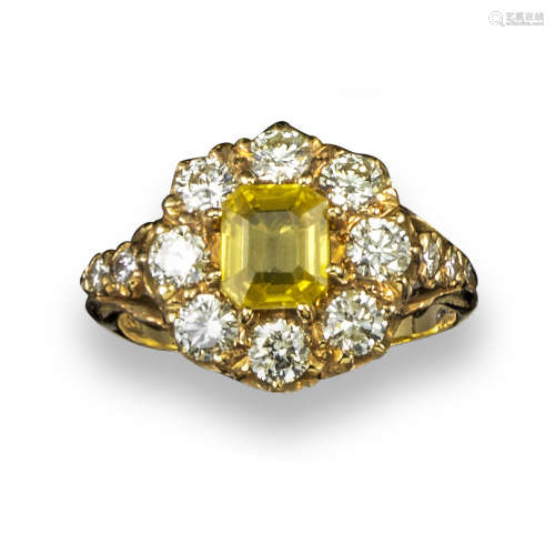 A yellow sapphire and diamond cluster ring, the emerald-cut yellow sapphire set within a surround of