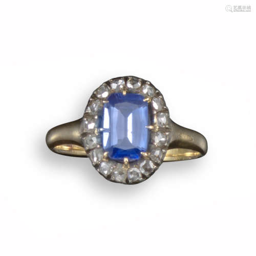 A sapphire and diamond cluster ring, the step-cut sapphire is set within a surround of rose-cut