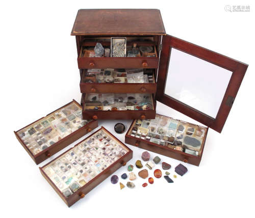 A wooden specimen cabinet, containing a variety of cased gemstones, including a large rough ruby and
