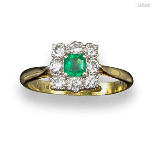 An emerald and diamond cluster ring, the emerald-cut emerald set within a surround of circular-cut