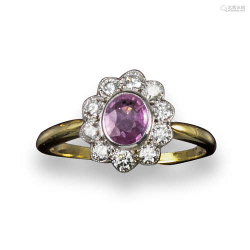A pink sapphire and diamond cluster ring, the oval-shaped pink sapphire set within a surround of ten