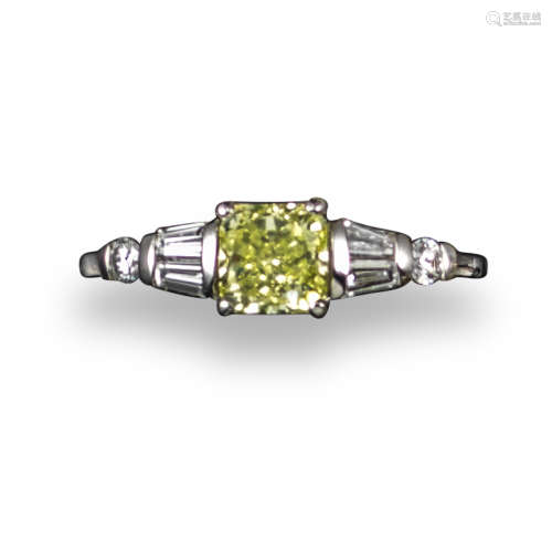 A fancy yellow diamond ring, the cushion-shaped diamond weighs 1.01cts, within tapered baguette