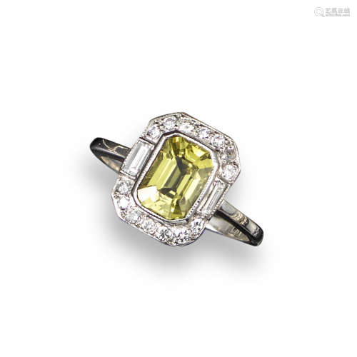 A yellow sapphire and diamond cluster ring, the emerald-cut sapphire is set within a surround of