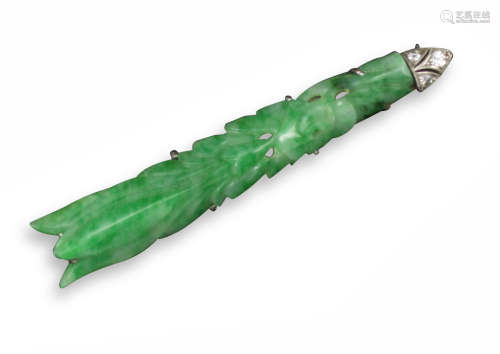 An early 20th century carved and pierced jade stylised arrow brooch, the tapered jade is mounted