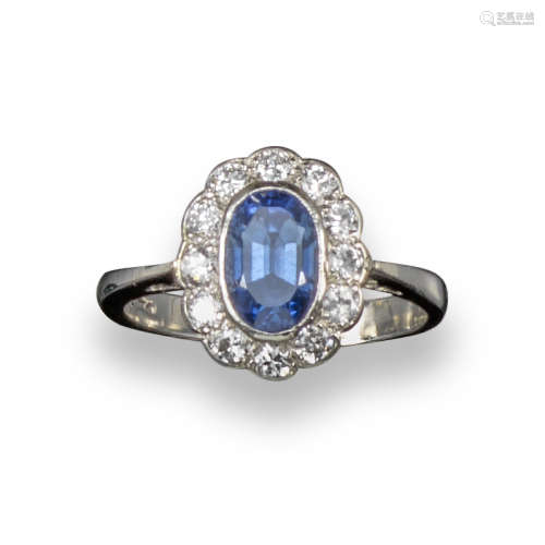 A sapphire and diamond cluster ring, the oval-shaped sapphire set within a surround of circular-