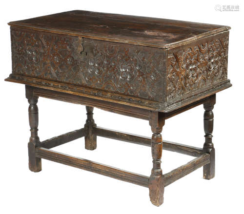 An early 17th century West Country oak box, the boarded hinged top above a carved front and sides,