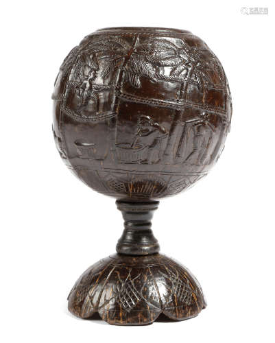 A carved coconut cup, naively carved in relief with natives in various pursuits: climbing palm