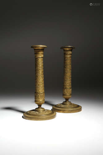 A matched pair of French Empire ormolu candlesticks, each with a detachable drip-pan, decorated with