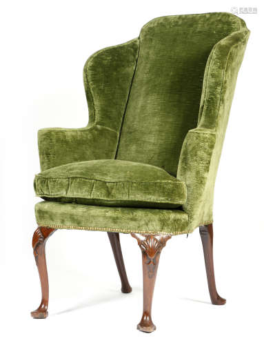 A George II red walnut wing armchair, later upholstered with green plush fabric, on shell and husk