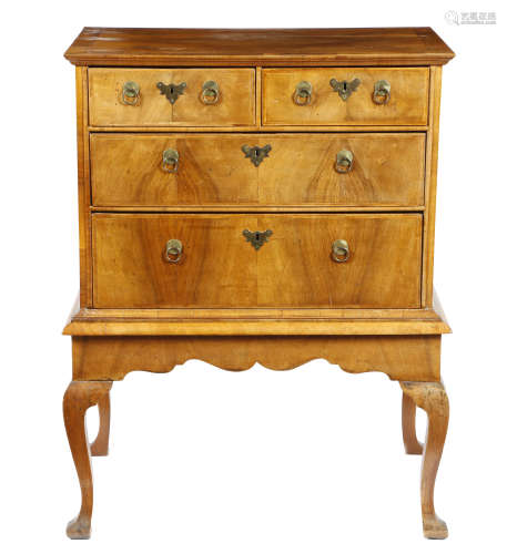 A walnut chest on stand, the quarter veneered top with cross and feather banding, above two short