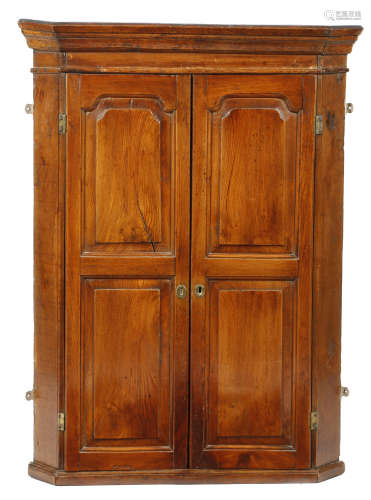A mid-18th century elm and oak hanging corner cupboard, with a pair of fielded panel doors enclosing