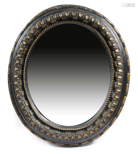 An early 18th century carved oak and ebonised oval wall mirror, with parcel gilt decoration, the