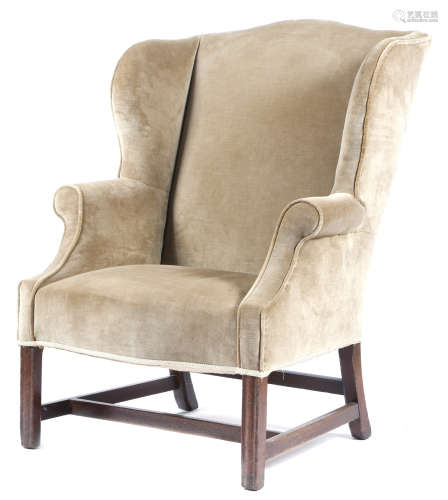 A George III mahogany wing armchair, later upholstered with plush fabric, with a serpentine front