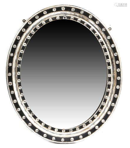 An Irish ebonised and silvered wood oval wall mirror, the moulded frame decorated with faceted cut-