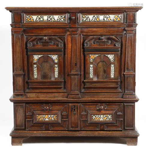 A 17th century oak enclosed chest, with a panelled frieze drawer, decorated with ebony panels,