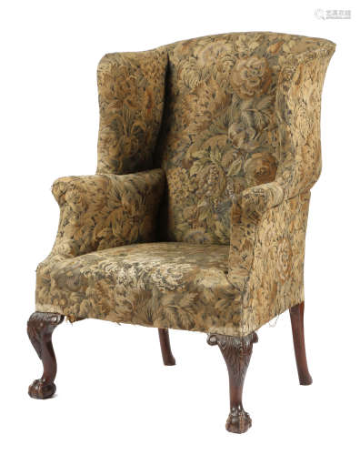 A mahogany wing armchair in George II style, with scroll arms, on leaf carved and cabriole front