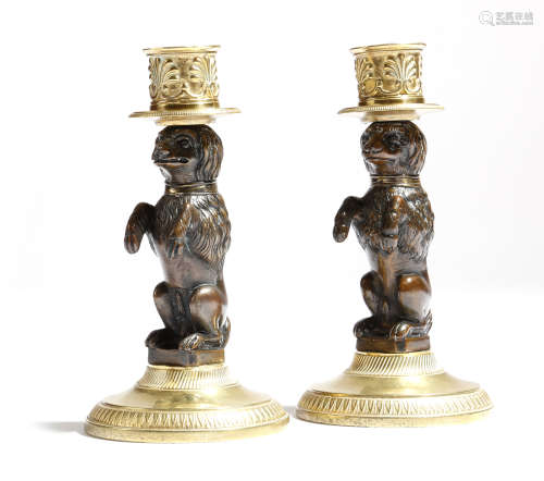 A matched pair of gilt and patinated bronze dog candlesticks, each modelled with a performing