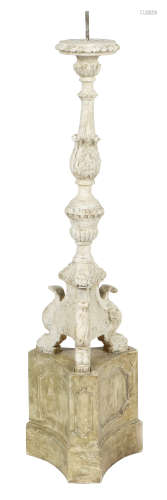 An Italian carved and painted wood altar candlestick, with a leaf carved baluster stem, on a triform