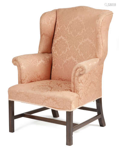 A mahogany wing armchair in George III style, later upholstered in pink damask fabric, on moulded
