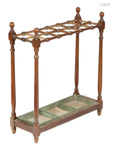 A late Victorian walnut stickstand, with twelve divisions and a green painted metal lift-out tray,