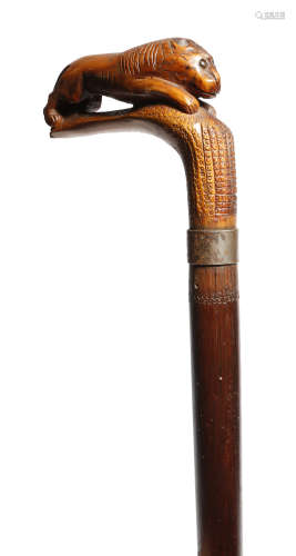 A folk art hardwood walking cane, the handle carved with a lion, with a metal ferrule, 85.4cm long.