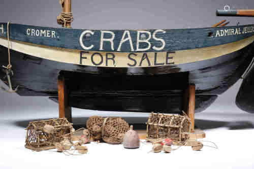 A folk art painted wood model crab boat shop sign, with three oars, two crab pots and nets,