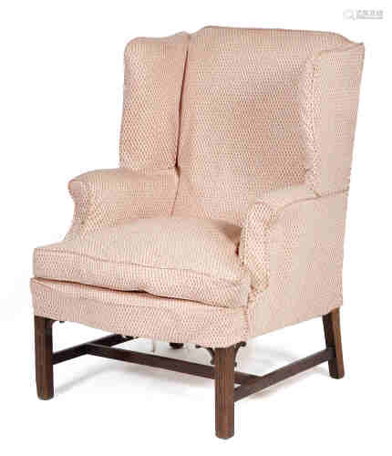 A mahogany wing armchair in George III style, covered in pink lattice design covers, on moulded