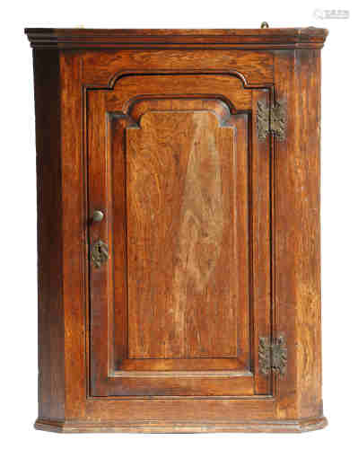 A mid-18th century oak hanging corner cupboard, with a fielded panel door, 89cm high, 66.8cm wide,