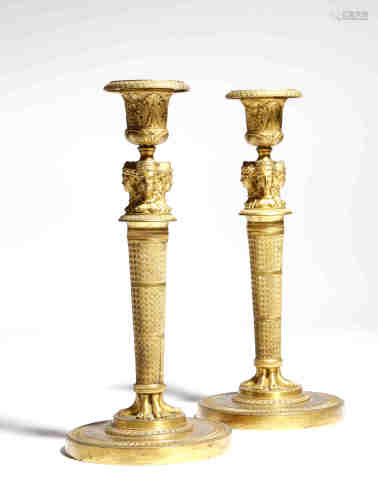 A pair of French Empire ormolu candlesticks in the manner of Jean-Demosthene Dugourc, each with a