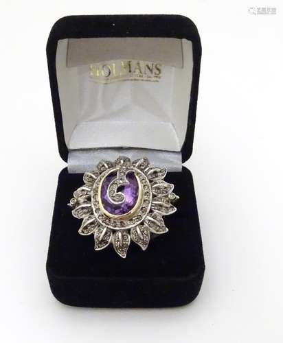 An 18ct gold ring set with large central amethyst adorned and bordered by a profusion of diamonds.