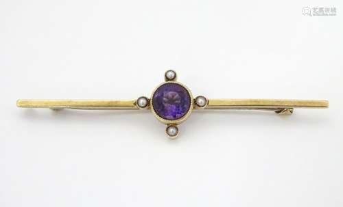 A late 19thC / early 20thC 15ct gold bar brooch set with central amethyst and four seed pearls.