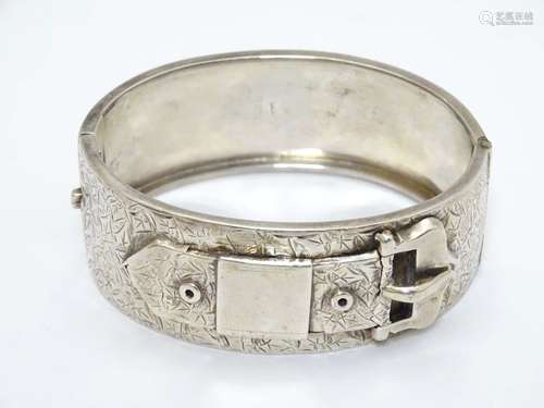 A Victorian silver bracelet of bangle form with buckle detail and engraved decoration.