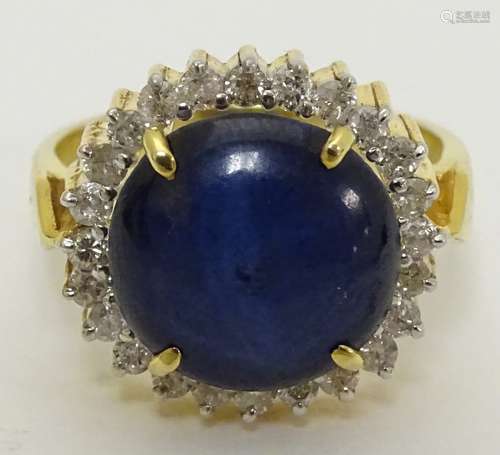 A 14k gold ring set with central blue sapphire cabochon bordered by diamonds CONDITION: