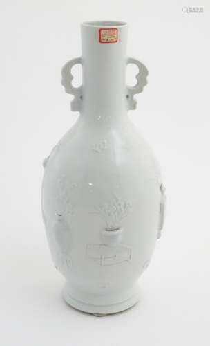A white celadon bottle vase with relief decoration of flowers in vases and Chinese characters,