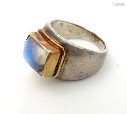 A Retro white metal cocktail ring set with moonstone cabochon in a yellow metal setting.